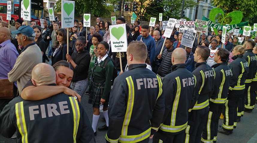 A demonstrator hugs a firefighter at a Grenfell vigil