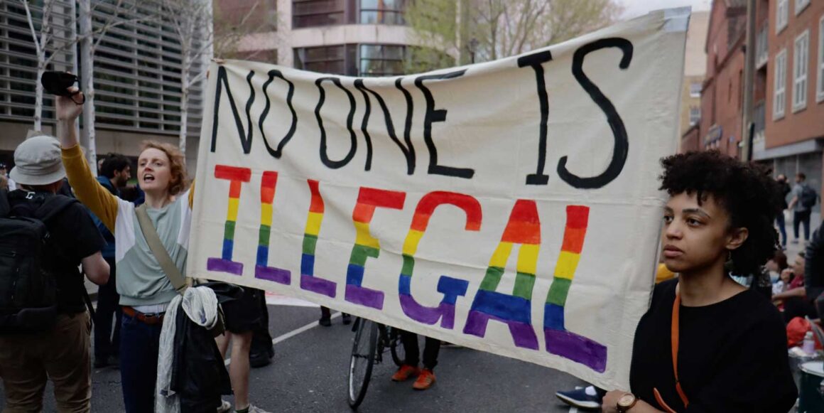 Activists hold a banner reading 'No-one is illegal'