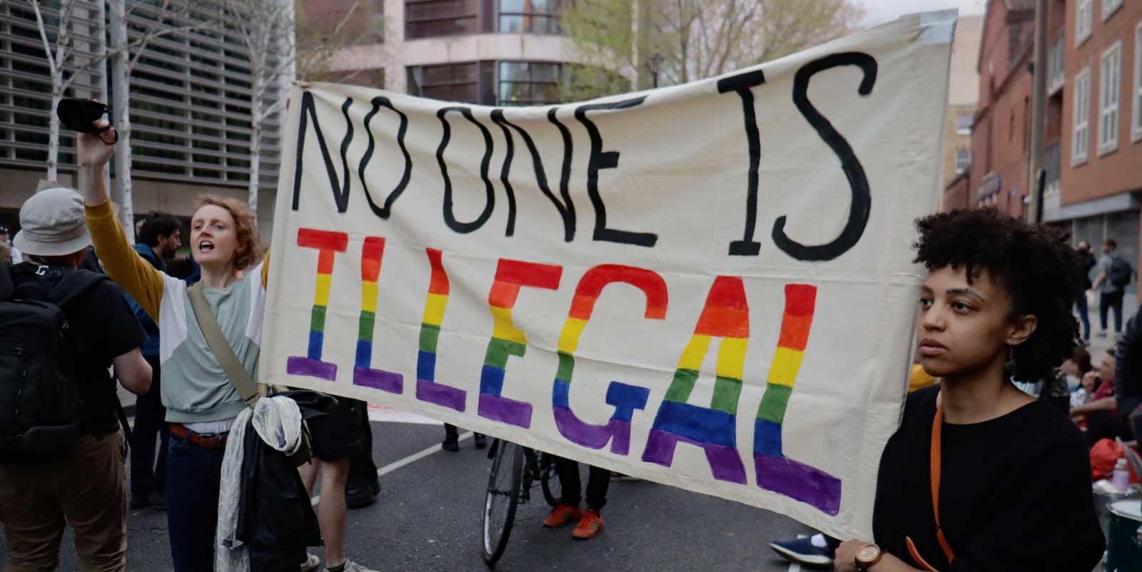 Activists hold a banner reading 'No-one is illegal'
